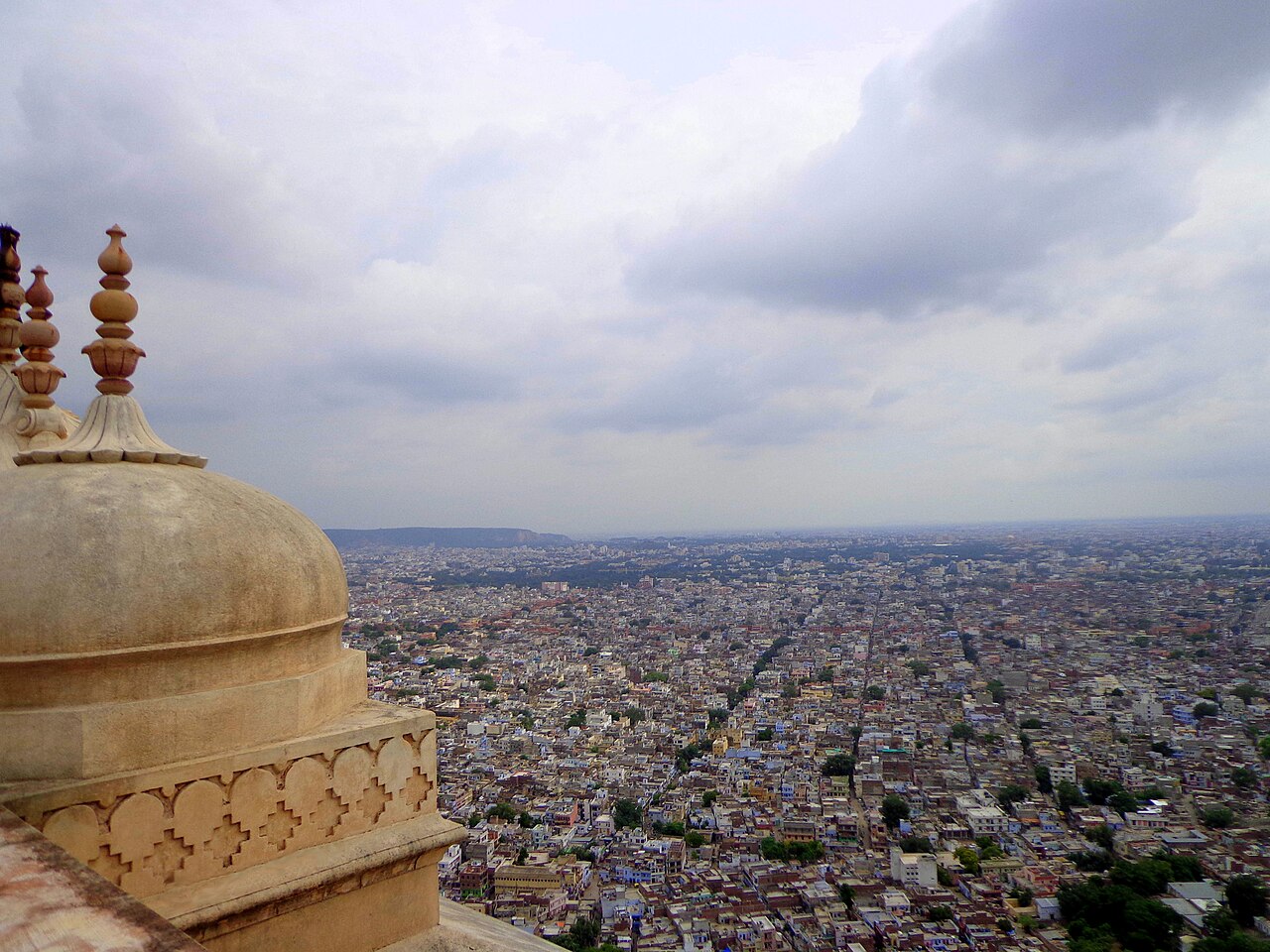 Jaipur spreading beneath a cloudy sky, seen from Nahargarh Fort.